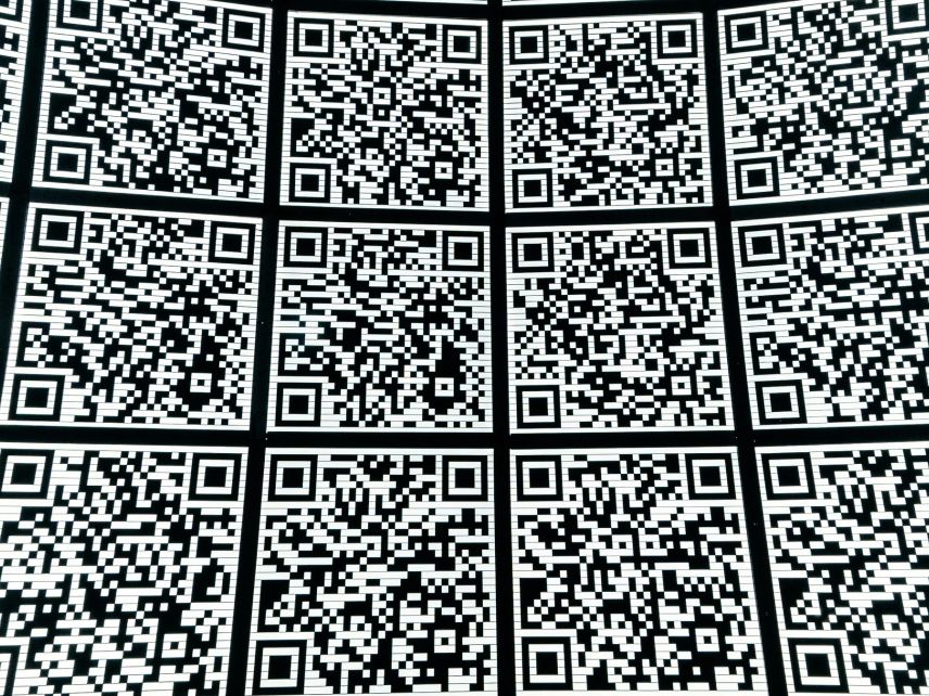 A curved wall covered in dozens of near-identical black and white QR codes