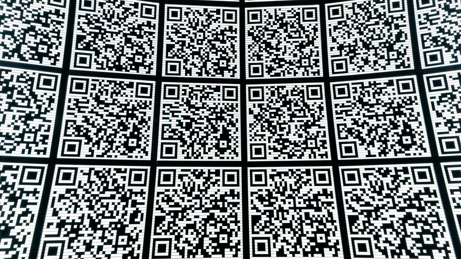 A curved wall covered in dozens of near-identical black and white QR codes